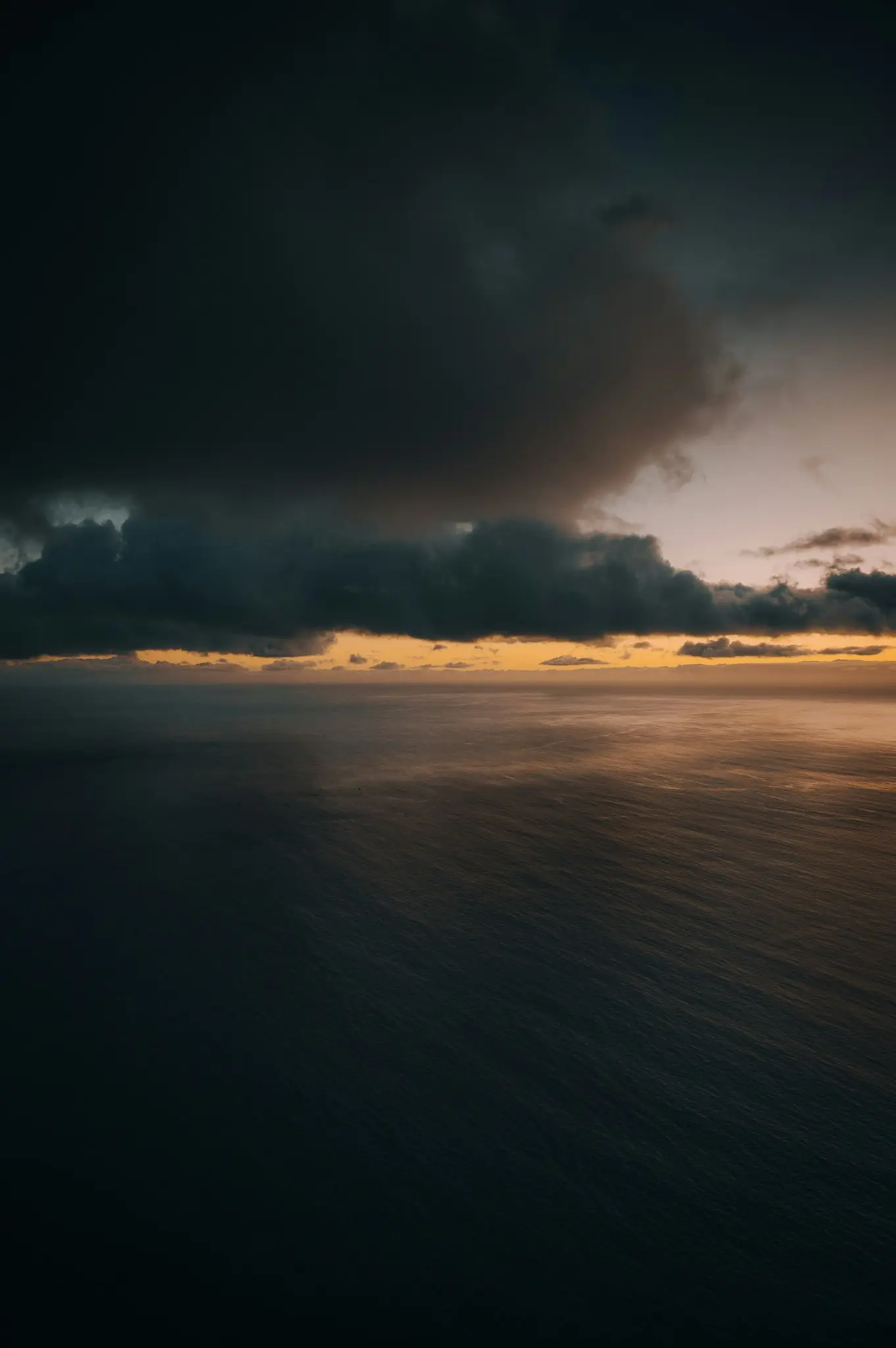 夕暮れの海にかかる暗い雲